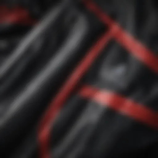 Close-up of the black Adidas jacket showcasing the iconic red stripes design.